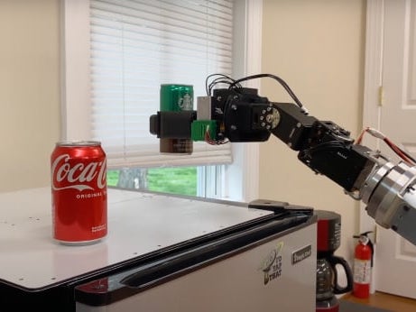 Side view of Model R2 Robotic Manipulator Arm grasping and lifting a can from the top of a mini refrigerator
