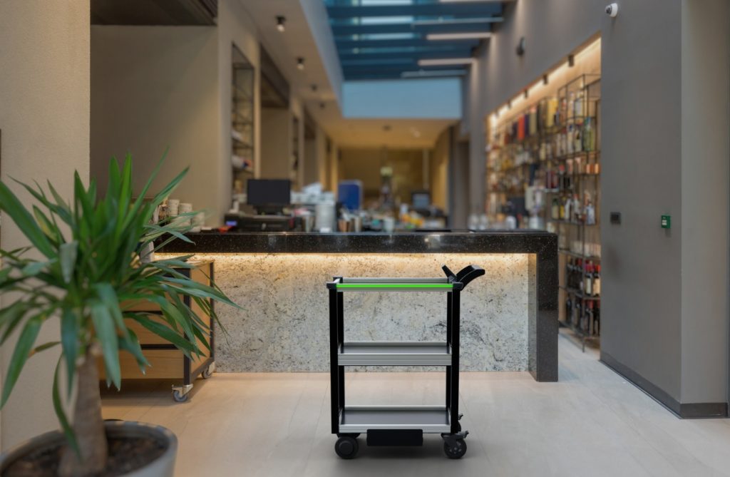 Model C2 Autonomous cart stands in front of a reception desk in a hotel that employs robot carts