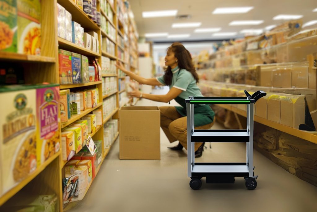 Model C2 autonomous cart in a retail store environment with a human stocker unloading a delivered box behind the robot cart