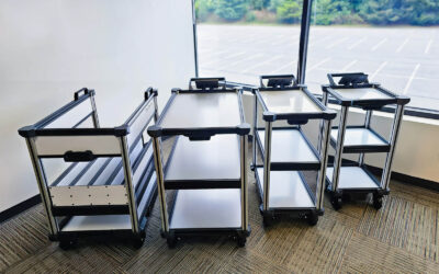 4 options of Model C2 AMR mobile delivery robot configurations, standing in a row in front of window